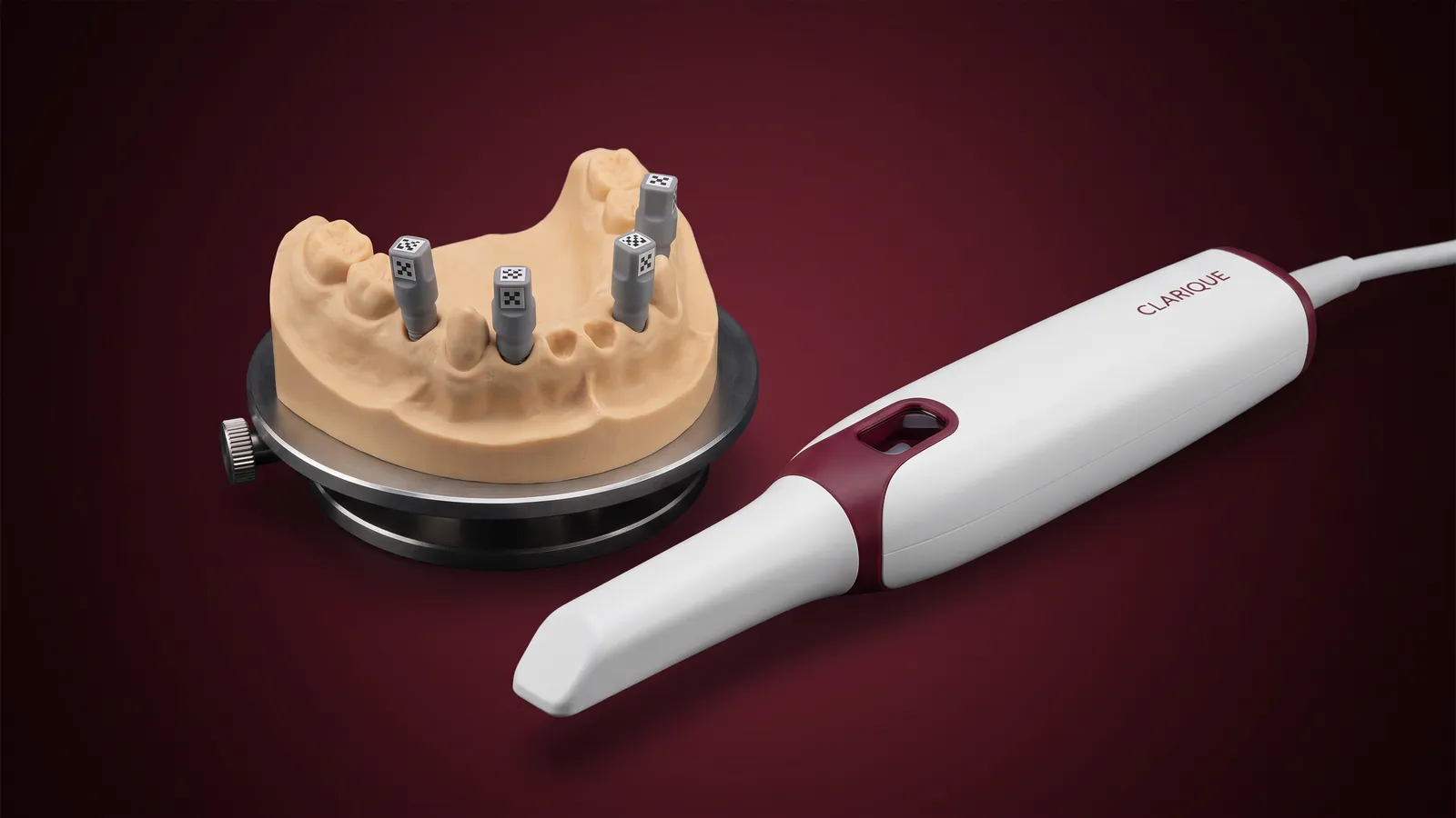Intraoralscanner neben einem Kiefermodell mit vier codierten Scanbodys auf Implantaten